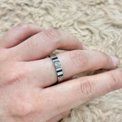 Close-up of a silver ring on a finger resting on a beige shag carpet.