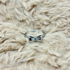 Close-up of light beige fluffy fur with a small shiny silver metal accessory at the bottom center.