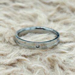 Close-up of a silver ring on beige fur, engraved with the words 'MISS YOU'.