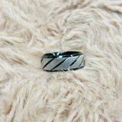 Close-up of a metallic bracelet with dark diagonal stripes resting on light beige fluffy fur