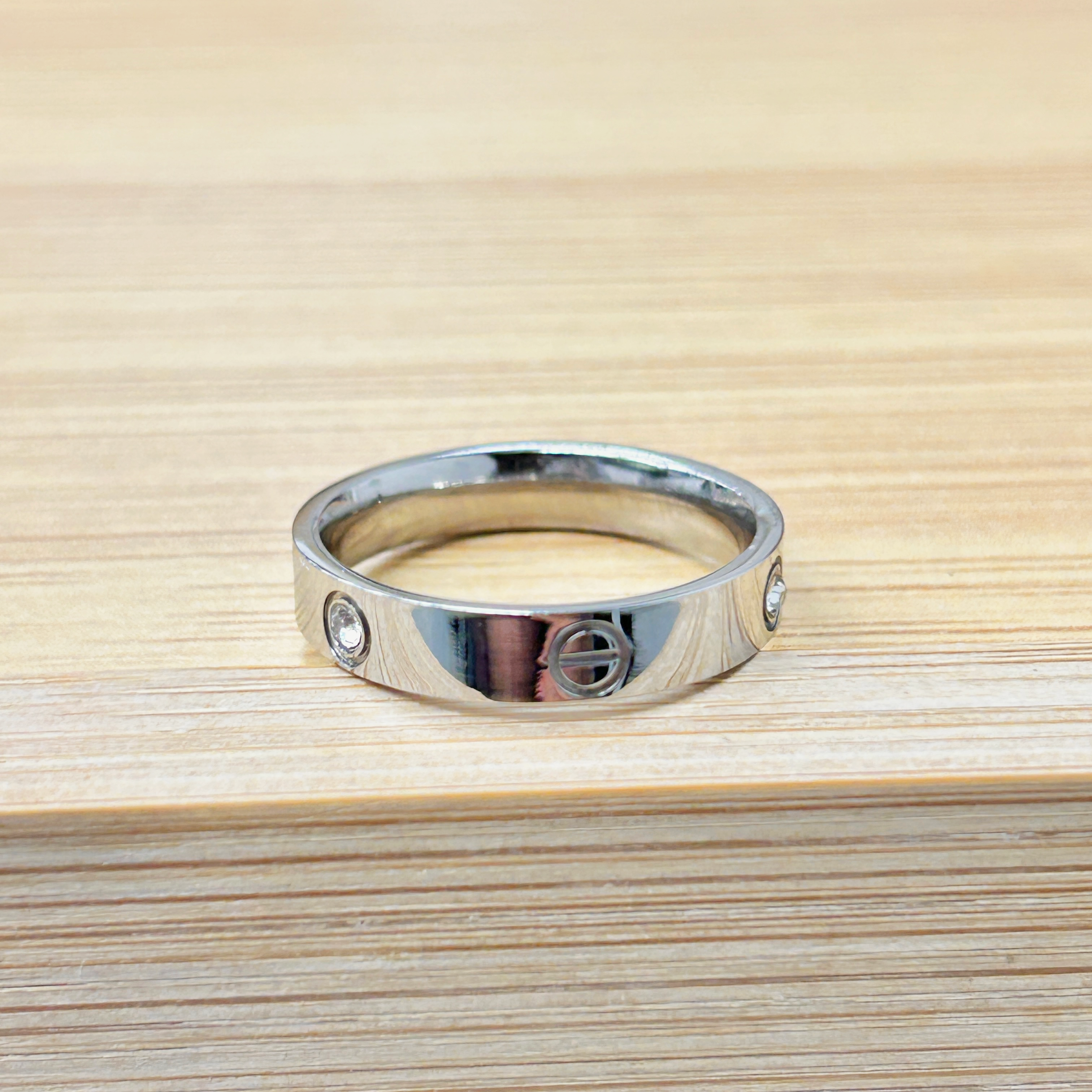 Close-up of a metal ring embedded in a light wood surface, with visible screws and a shiny chrome finish.