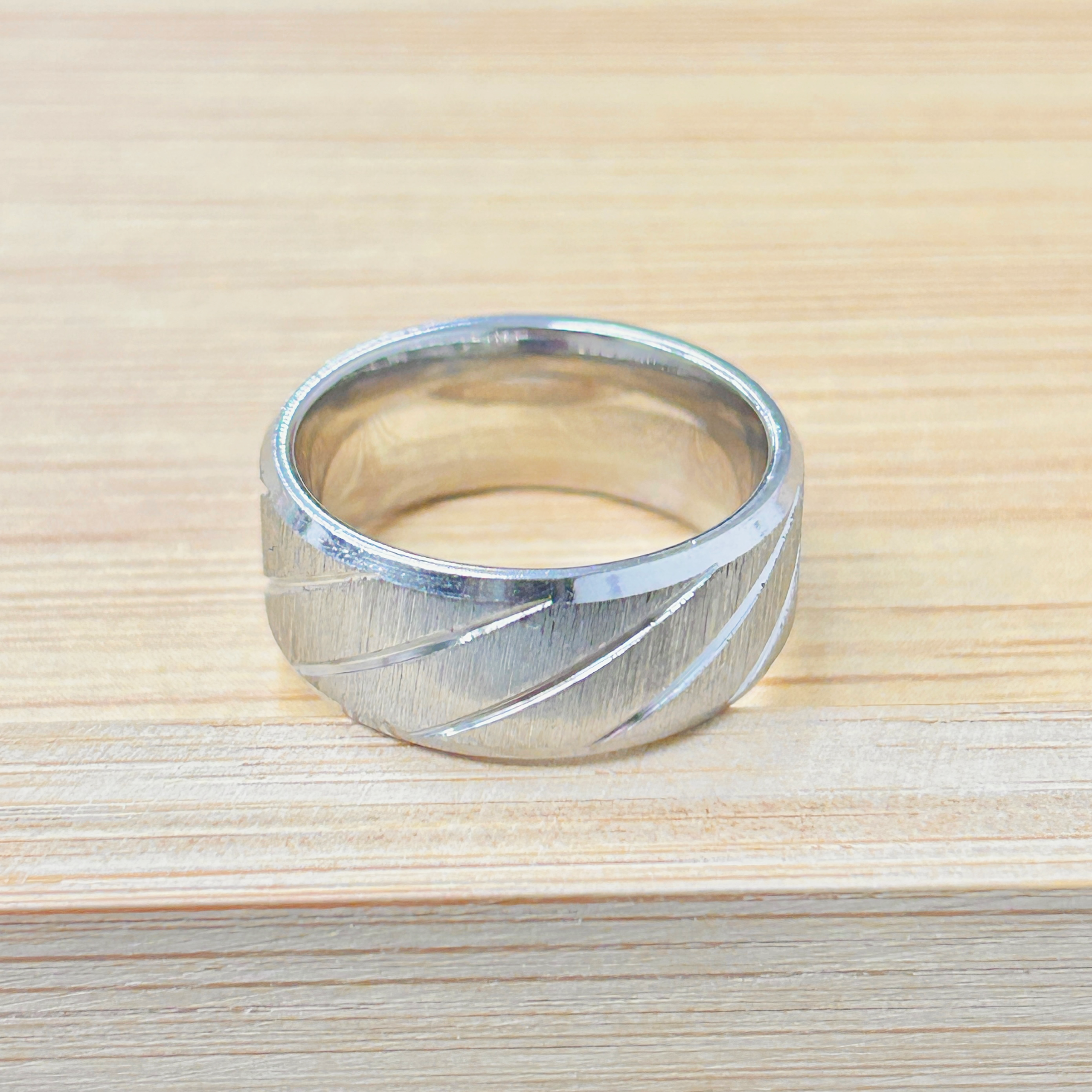Chunky Silver Diagonal Groove Ring picture2 - Eriy Gift Shiny metal ring resting on a light wooden surface, photographed from above.