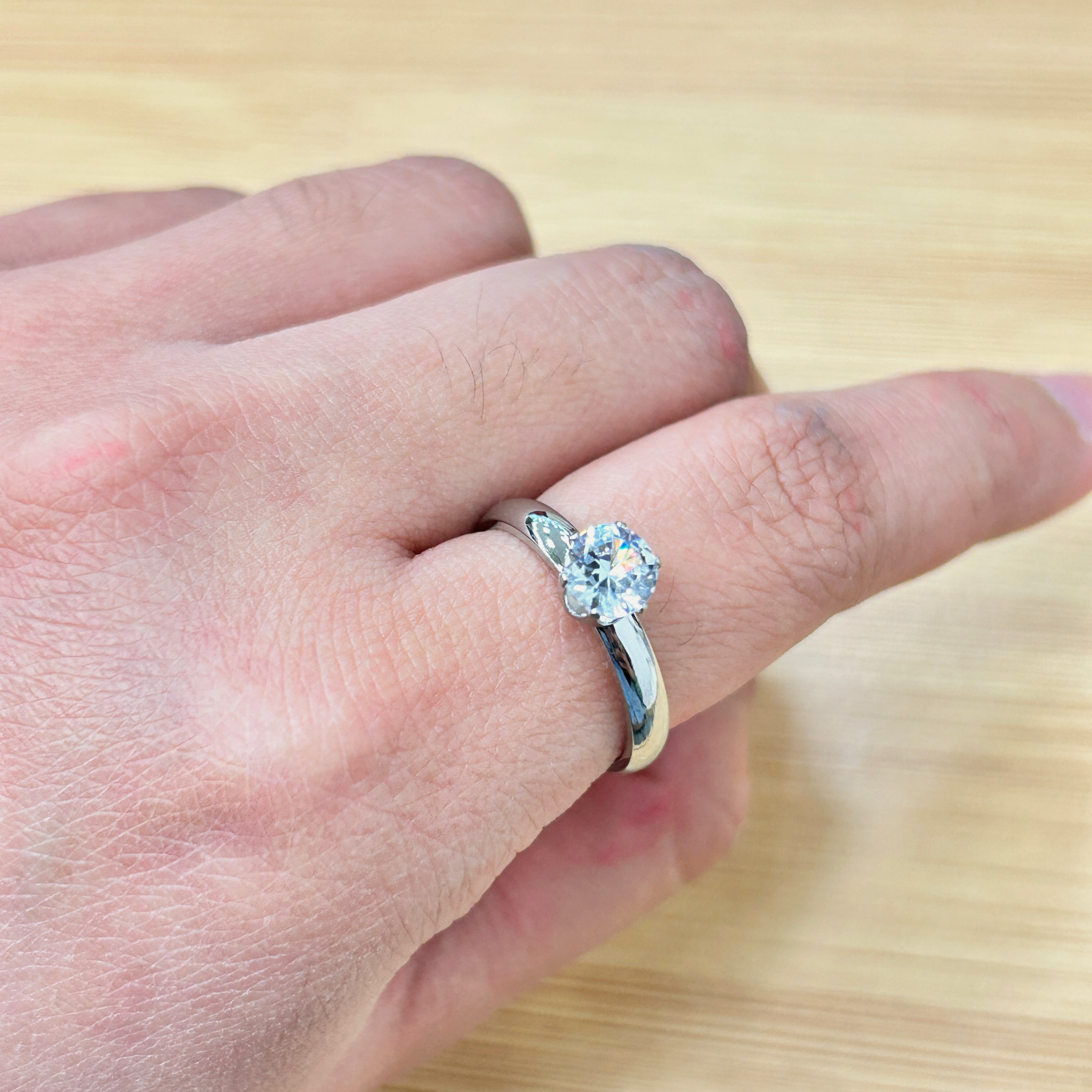 Close-up of a hand showing a sparkling diamond ring on the ring finger.
