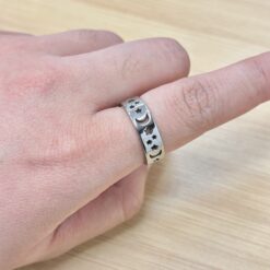 Dainty Silver Celestial Moon Star Hollow Ring - Eriy Gift Close-up of a hand wearing a silver decorative ring with star and crescent shapes on the ring finger, against a wooden background.