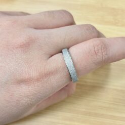 Dainty Silver Sandblast Glitter Promise Ring - Eriy Gift Close-up of a textured silver ring worn on a finger, with a light wooden surface in the background.