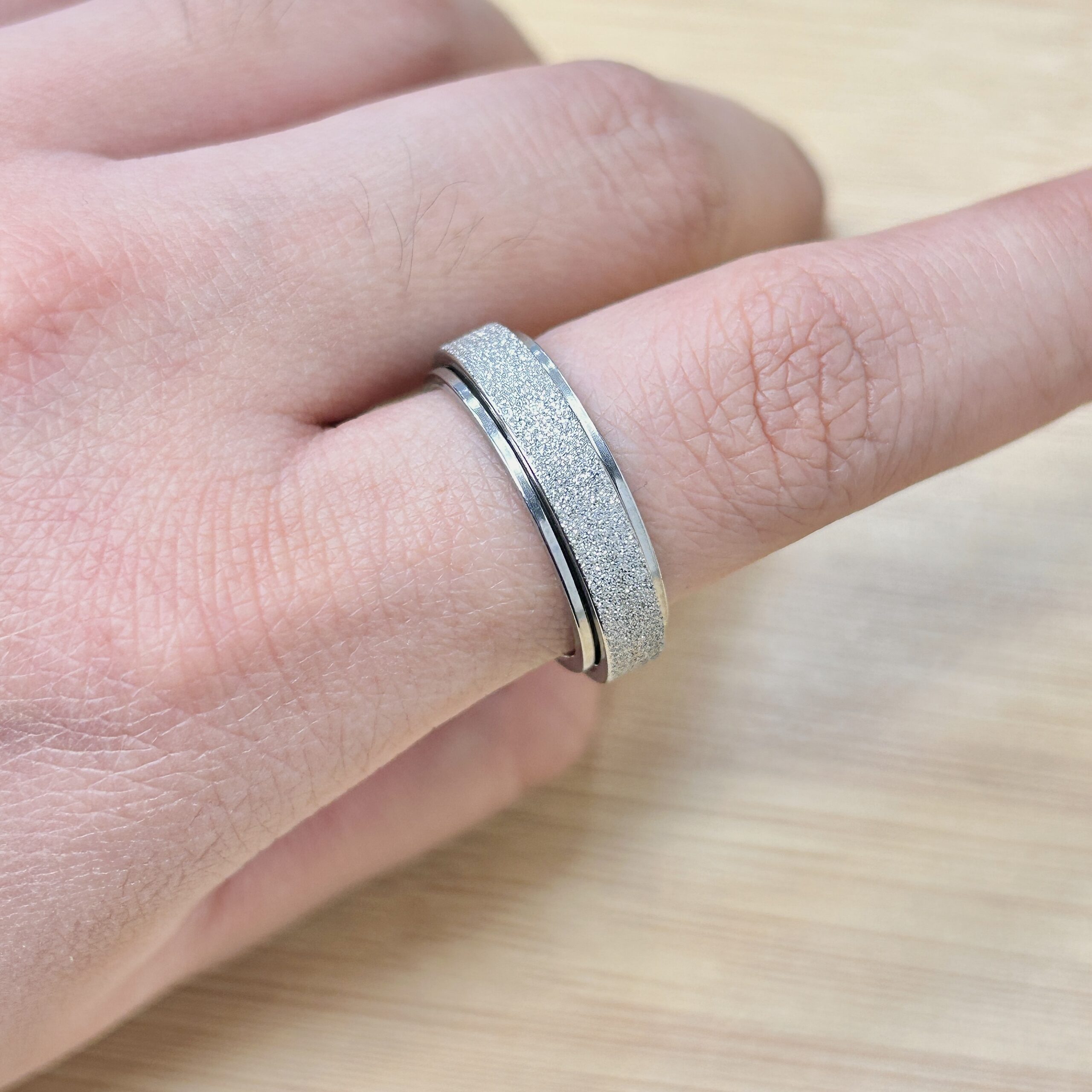 Dainty Silver Sandblast Glitter Spinner Ring - Eriy Gift Close-up of a silver textured ring worn on a finger.