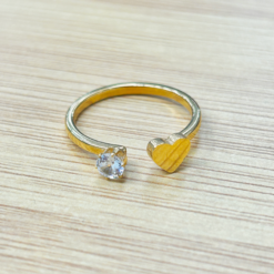 Close-up of a diamond engagement ring and gold wedding band on a light wooden surface.