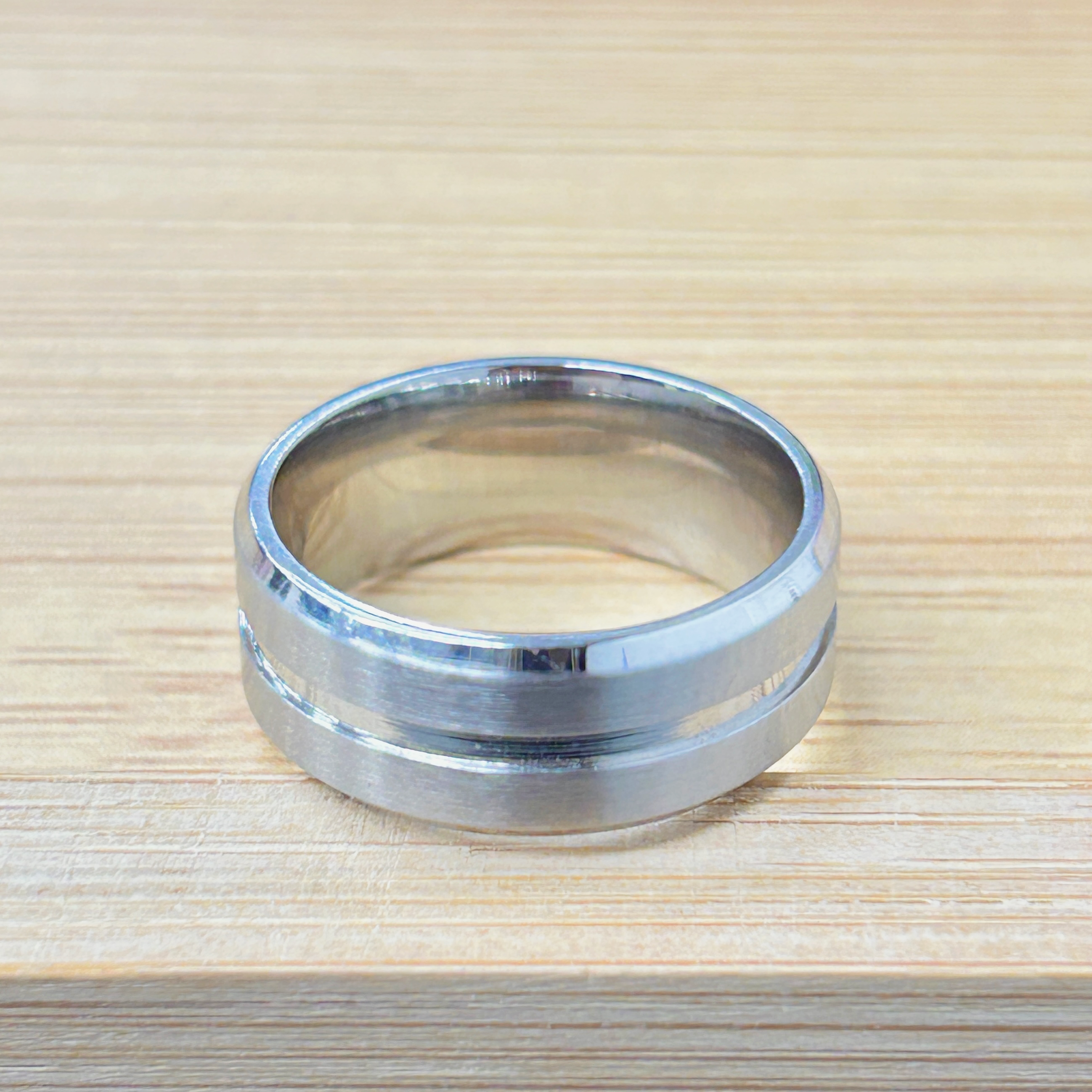 Shiny metal ring on a light wooden table, viewed from above.