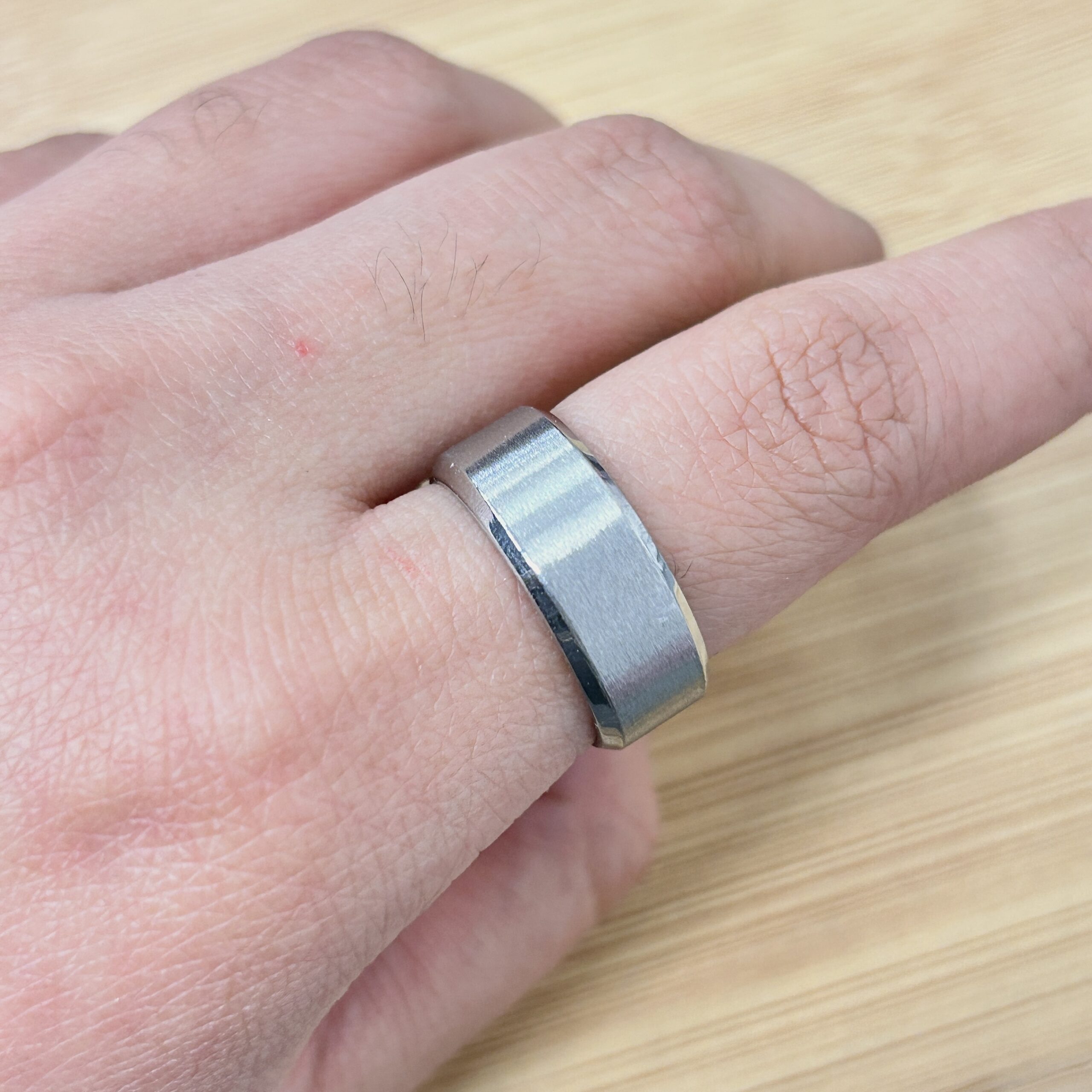Minimalist Matte Silver Plain Chunky Ring - Eriy Gift Close-up of a finger wearing a metallic ring with a tiny red skin spot nearby.