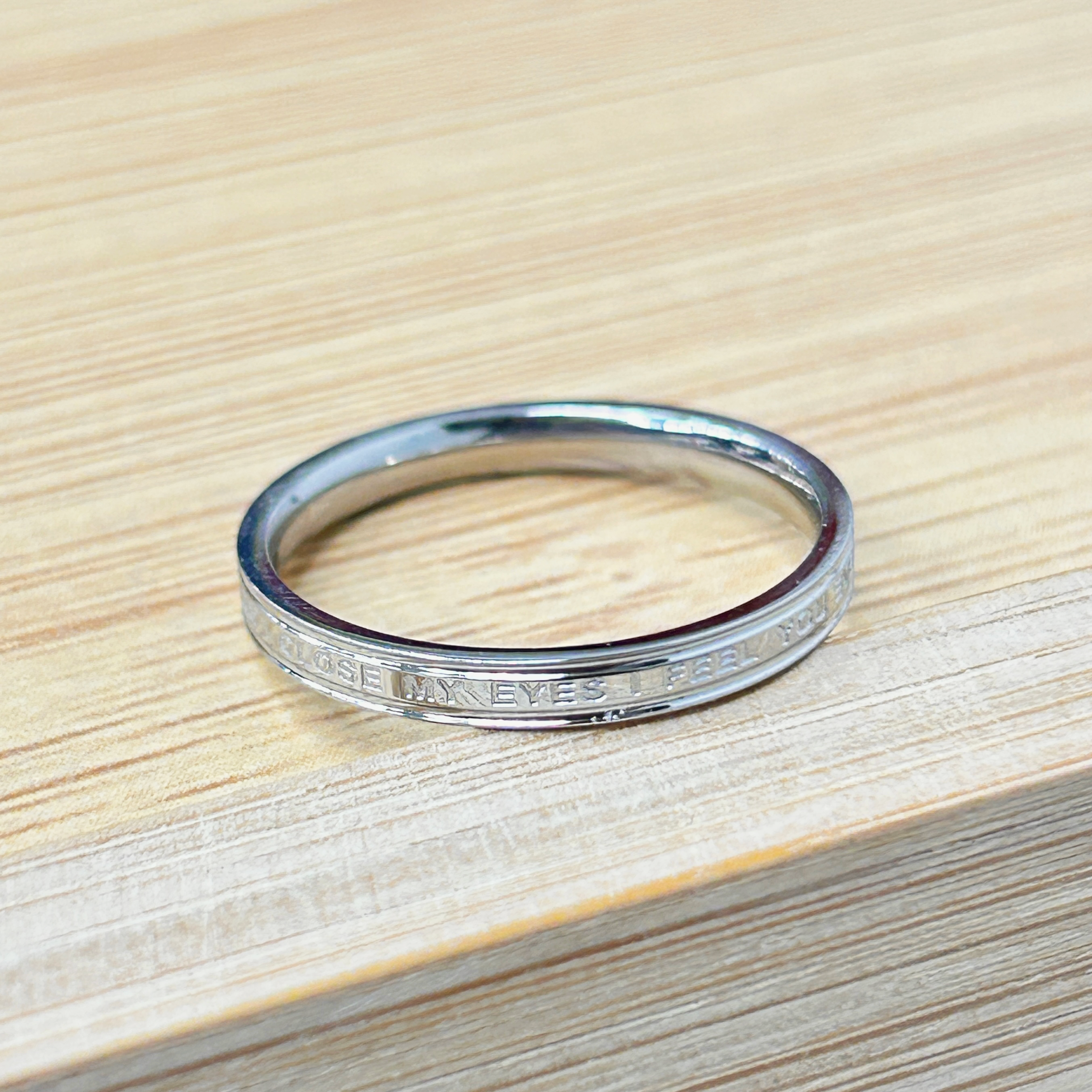 Shiny metallic ring on a light wooden table surface.