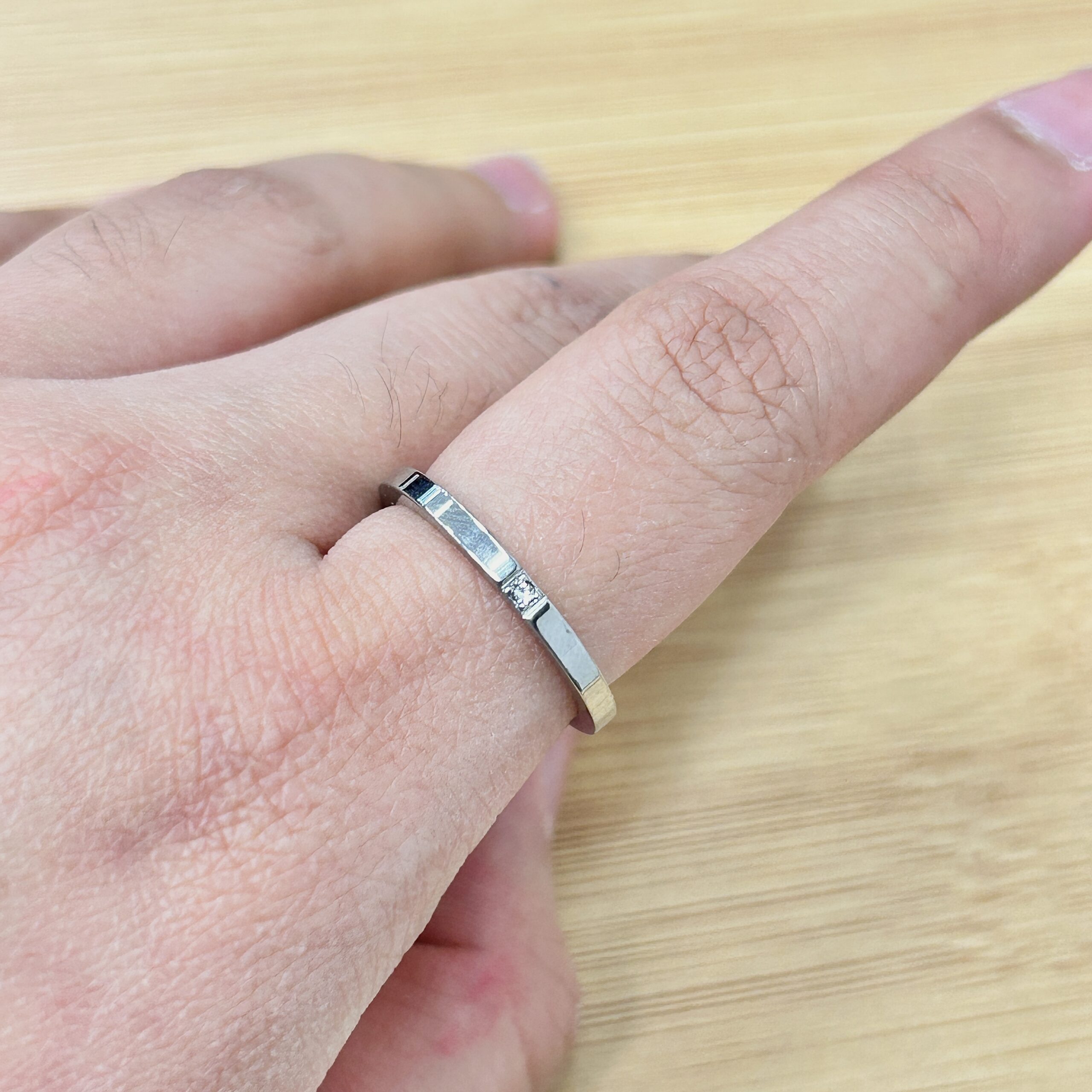 Minimalist Silver Single Zircon Band Ring - Eriy Gift Close-up of a finger with a silver ring, showing dry, reddish skin and small red spots nearby.