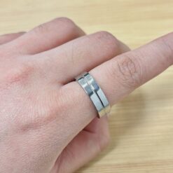 Polished Silver Center Groove Band Ring - Eriy Gift Close-up of a finger wearing a chunky silver band ring against a light wooden surface.