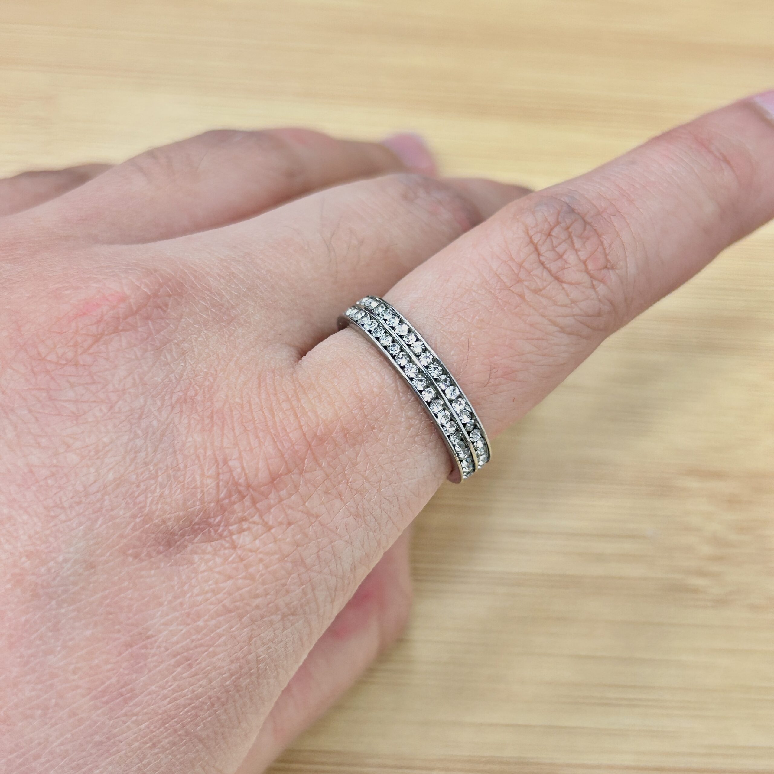 Close-up of a hand wearing a diamond-studded ring on the ring finger.