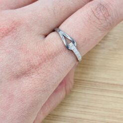 Close-up of a finger wearing a silver diamond-studded ring, with a metal jewelry tool near the band.