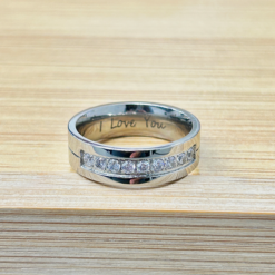 Silver ring on light wood with the inner engraving 'I love you' visible.