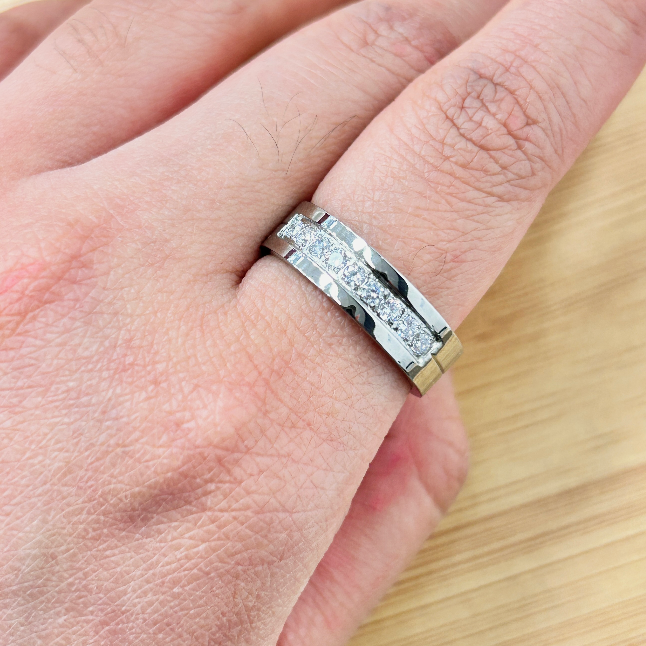 Close-up of a silver textured ring worn on a finger, showing the band and skin texture nearby.