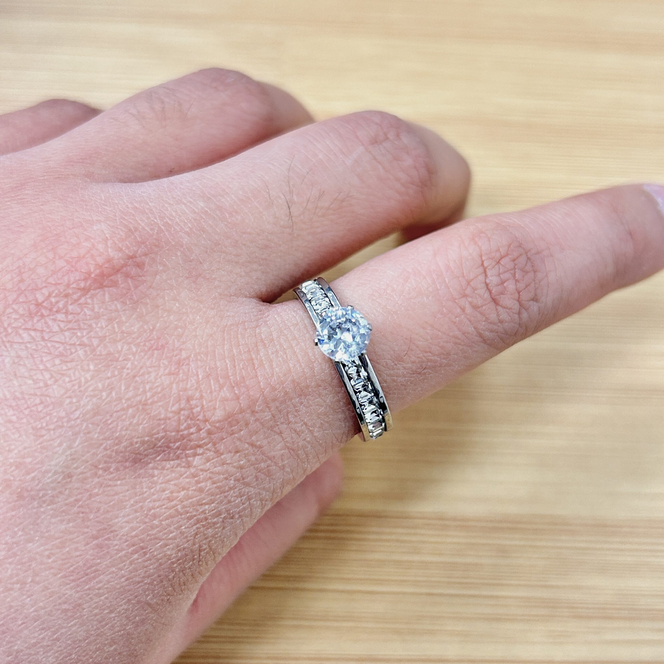 Close-up of a hand wearing a diamond eternity ring with pavé-set diamonds along the band