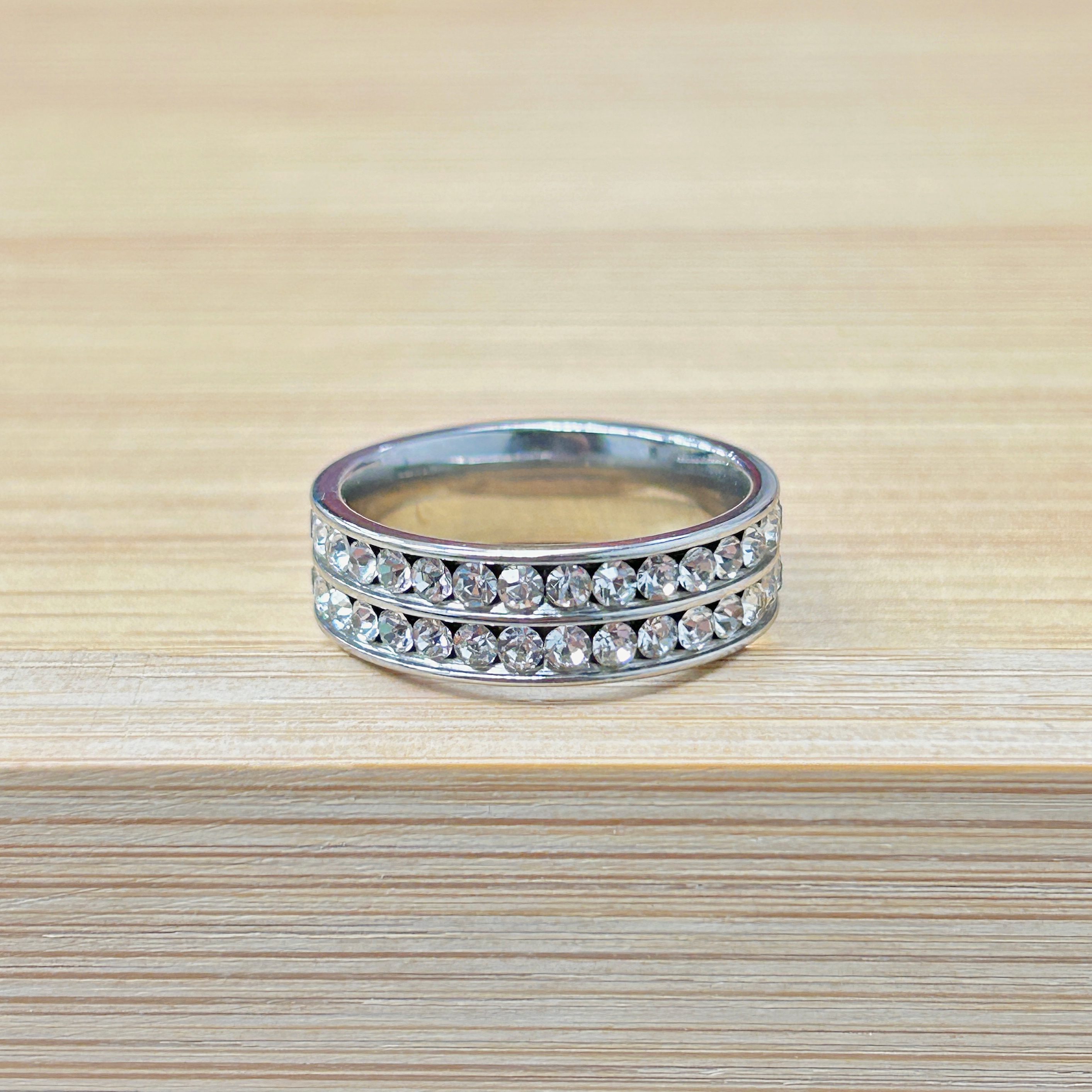 Stacked silver bracelet with clear rhinestones on a light wooden surface