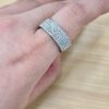 Close-up of a silver, diamond-studded band ring worn on a finger.