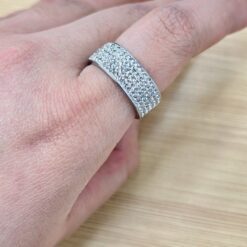 Close-up of a silver, diamond-studded band ring worn on a finger.