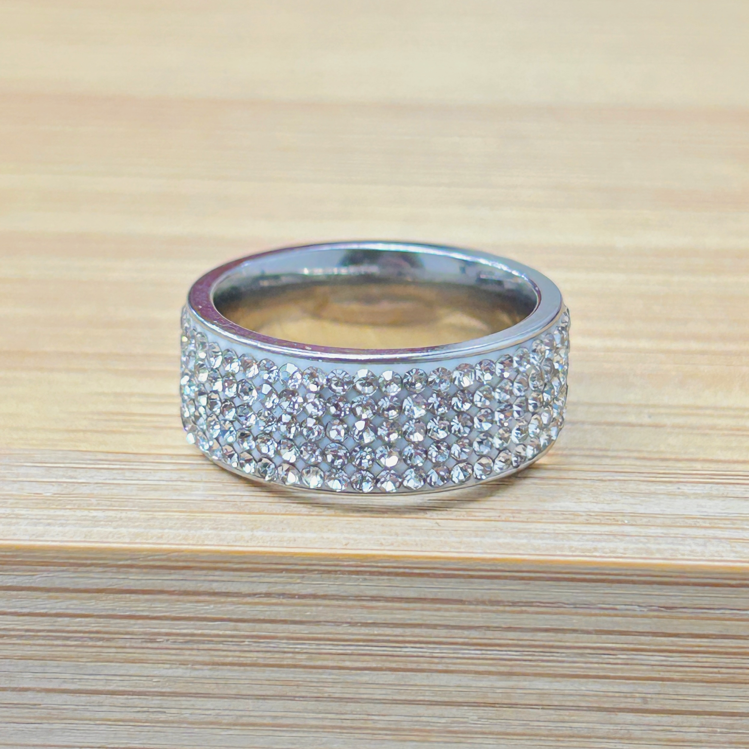 Silver Full Pave Zircon Chunky Ring picture2 - Eriy Gift Close-up of a silver rhinestone bracelet resting on a light wood table.