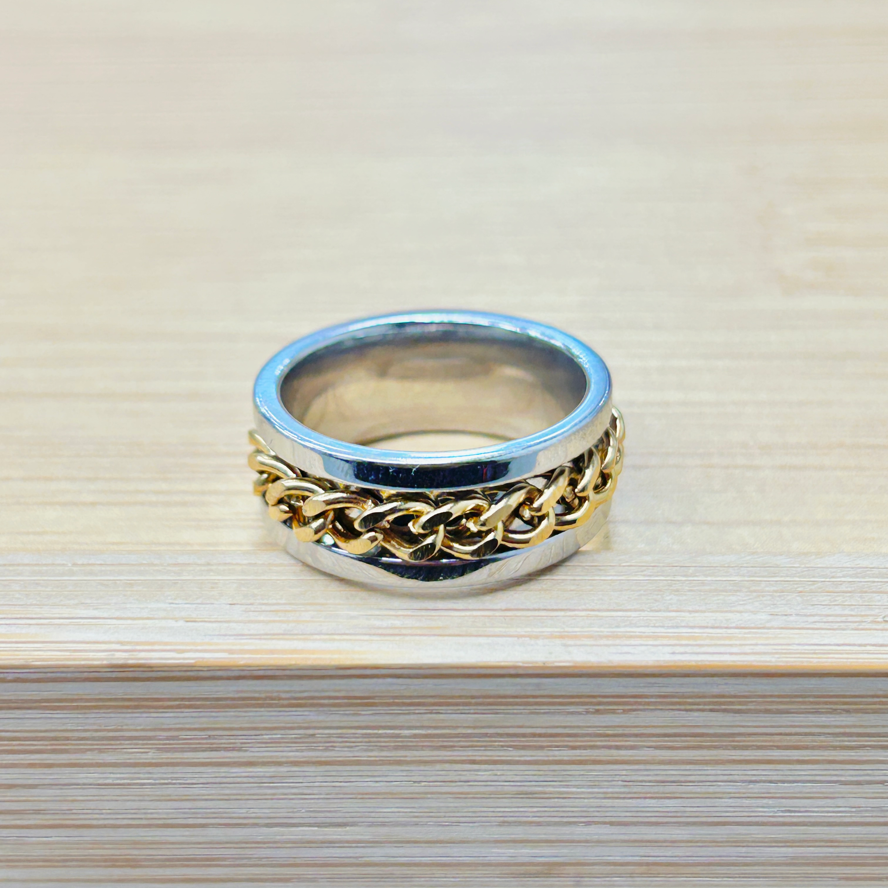 Stack of silver and gold-toned bracelets resting on a light wooden surface, captured from above.