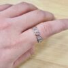 Close-up of a silver infinity-link chain bracelet resting on a finger.