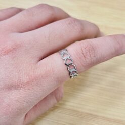Close-up of a silver infinity-link chain bracelet resting on a finger.