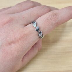Sleek Silver Olive Leaf Branch Ring - Eriy Gift Close-up of a hand wearing a silver leaf-link bracelet on the wrist, with a light wooden background.