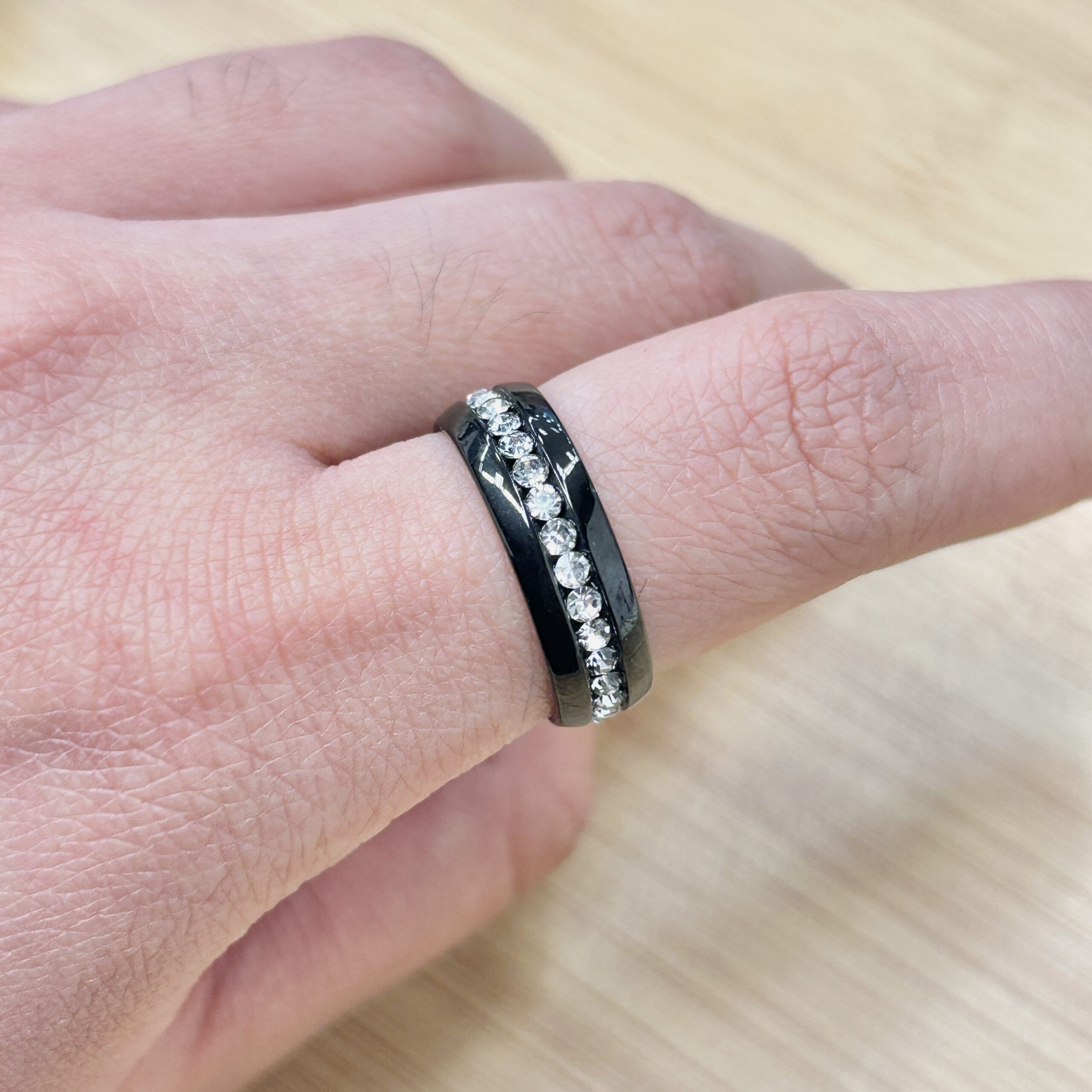Thick Rim Black Single Row Zircon Ring - Eriy Gift Close-up of a finger wearing a black metal ring with a row of clear diamonds set into the band.