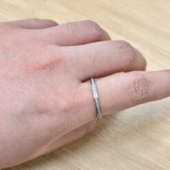 Thin Silver Sandblast Glitter Promise Ring - Eriy Gift Close-up of a wrist wearing a textured silver bracelet over bare skin, wood tabletop in the background.